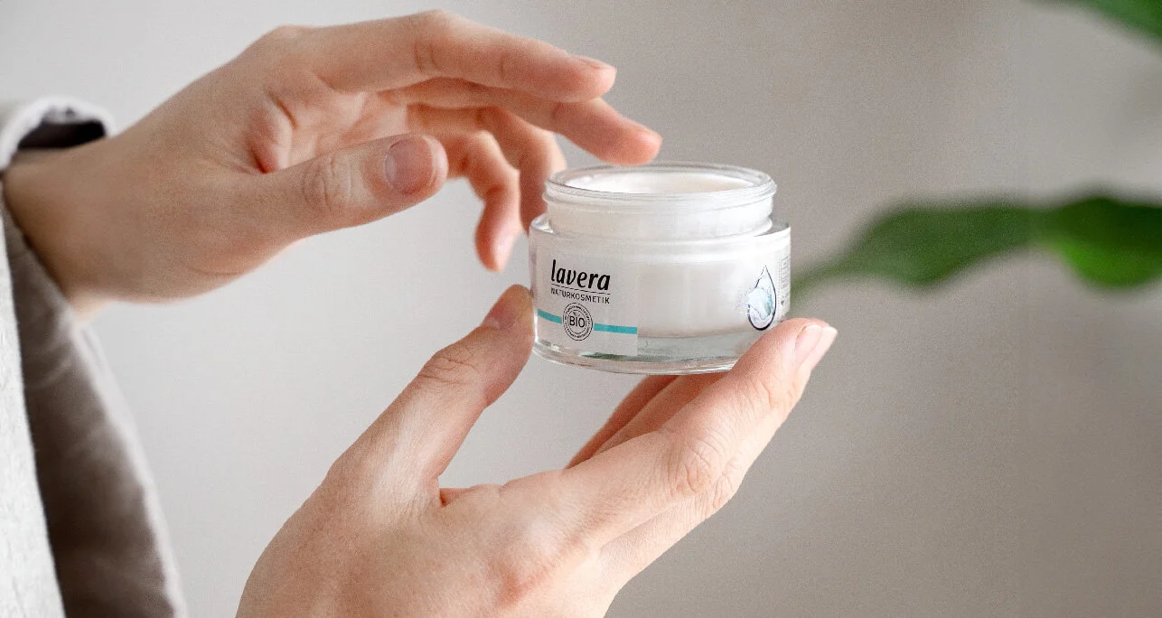 Mani che aprono un vasetto di crema per il viso